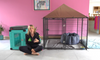 Lauren sitting in front of a crate and an enclosed puppy pen